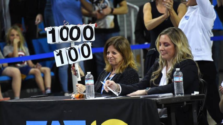 Collegiate gymnastics judge holds up a perfect 10 sign 